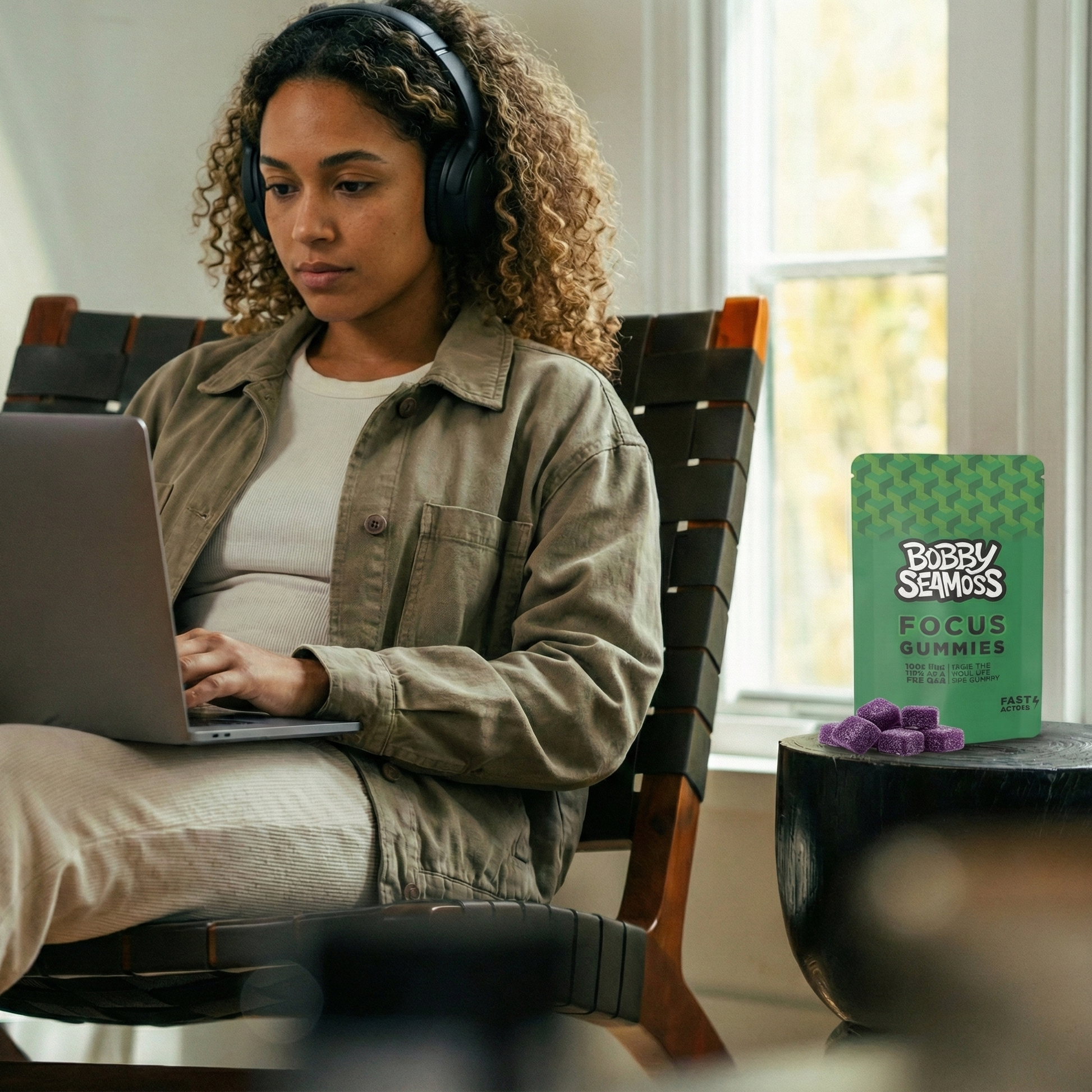 Woman using a laptop with a box of Bobby Seamus Focus Gummies on a table next to her.